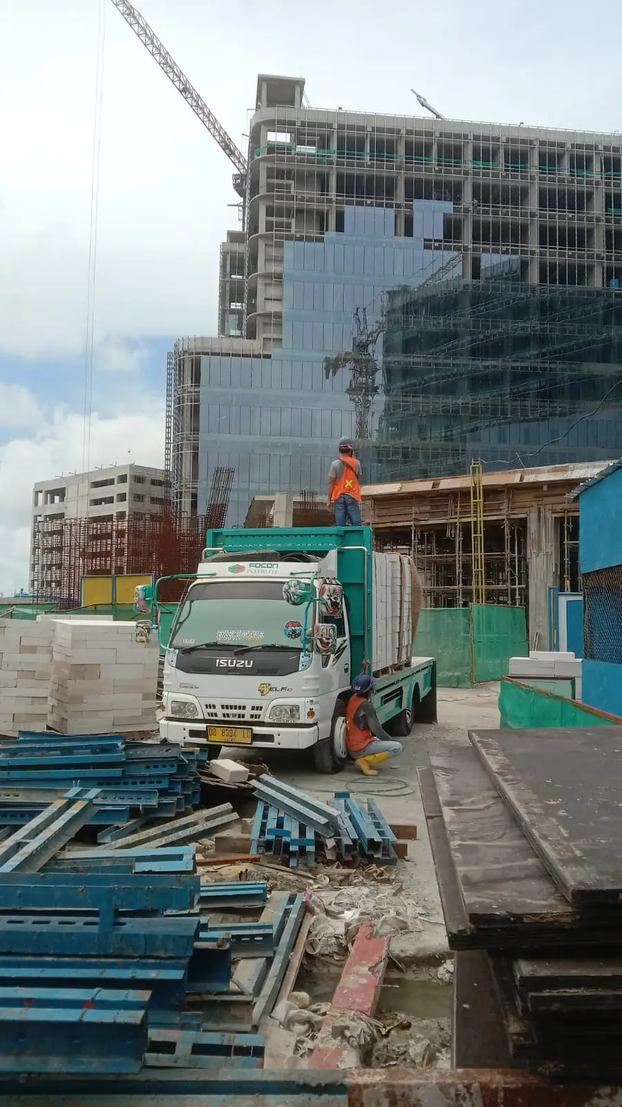 Truk bermuatan bata ringan dibongkar di proyek gedung perkantoran berdinding kaca