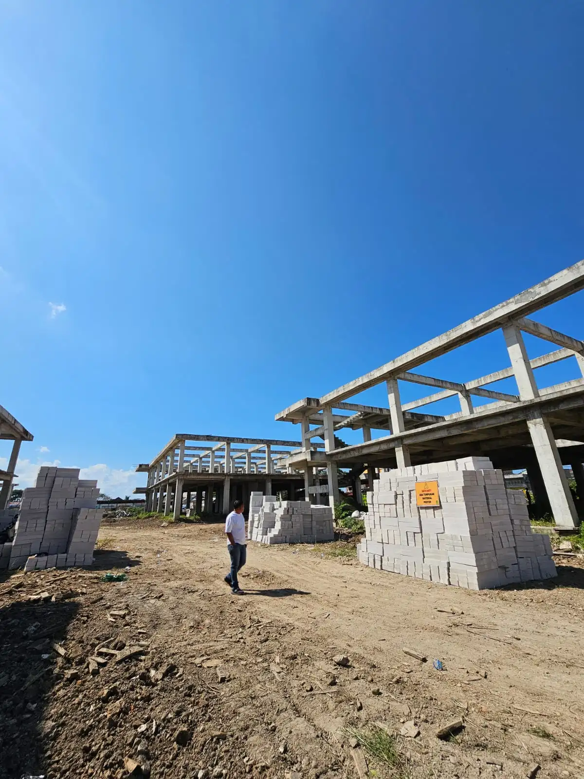 Peninjauan lokasi proyek gedung dengan tumpukan bata ringan siap pasang