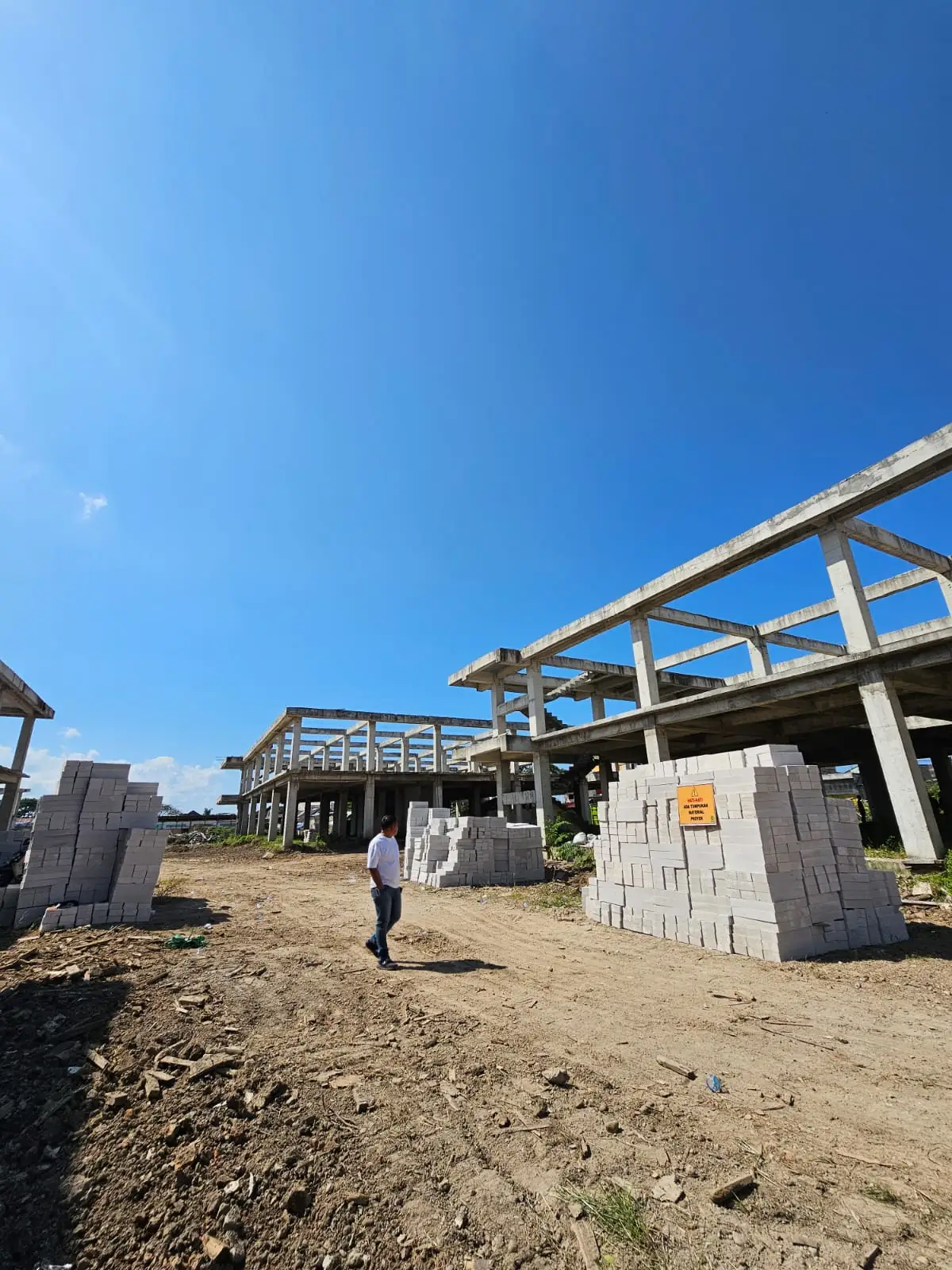 Rangka beton gedung bertingkat dengan tumpukan bata ringan siap pasang di lokasi proyek